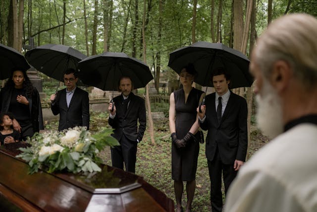 Funeral attendees holding black umbrellas in solemn reflection
